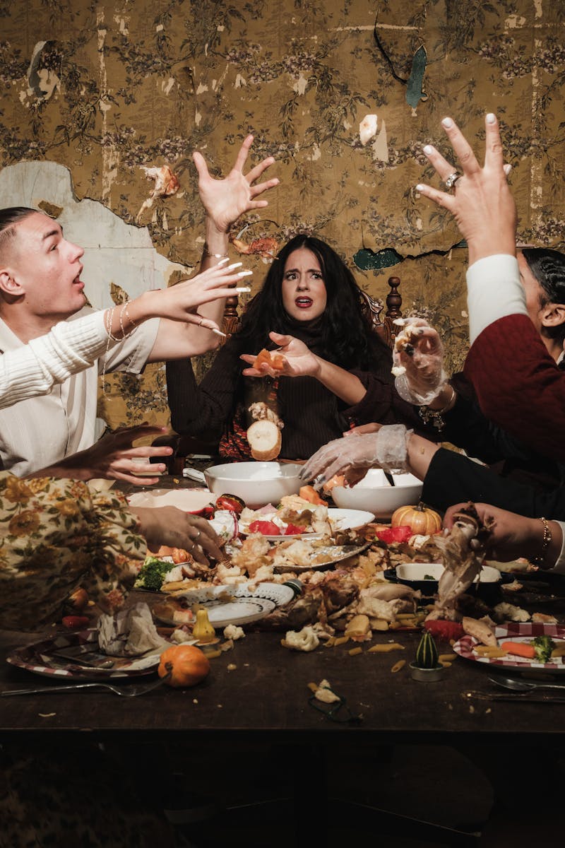 A lively scene of people engaging in a food fight around a festive dinner table.