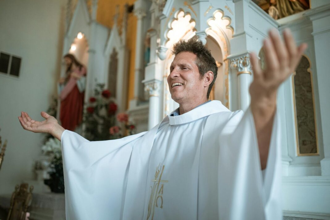 A smiling priest leads a prayer within a beautifully decorated church, embodying faith and spirituality.