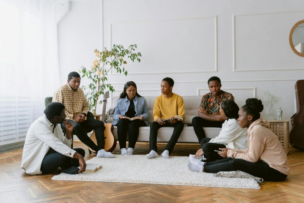 A diverse group of adults engaging in a discussion while sitting in a cozy living room.