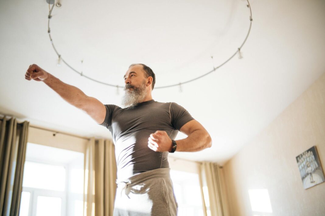 Elderly man performing yoga indoors to stay healthy. Emphasis on active lifestyle and wellness.