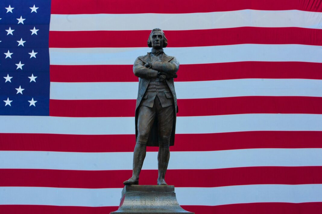 a statue of a man standing in front of an american flag