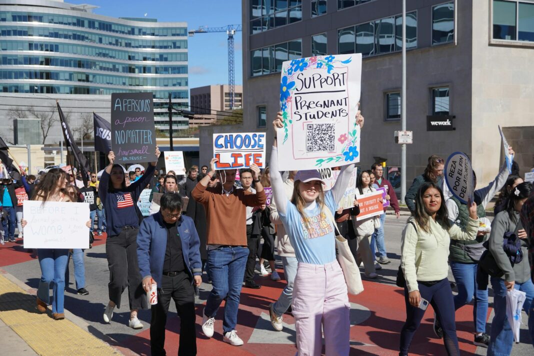 A group of people marching down a street holding signs