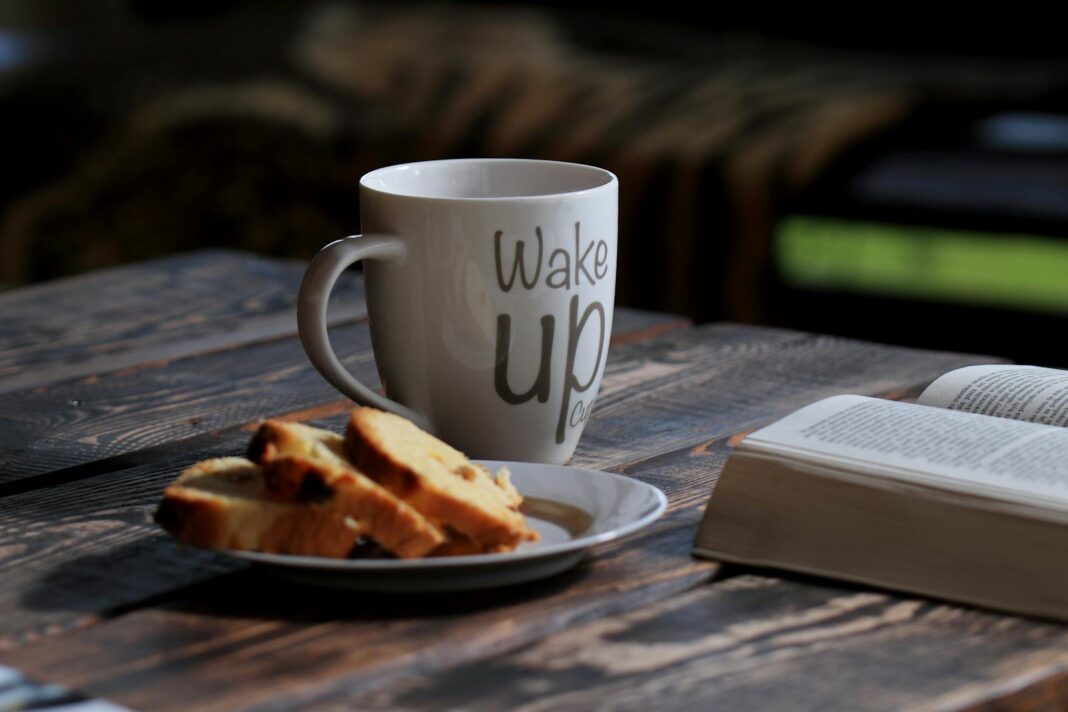 Enjoy a peaceful morning with a warm cup of coffee, opened book, and delicious pastries on a wooden table.