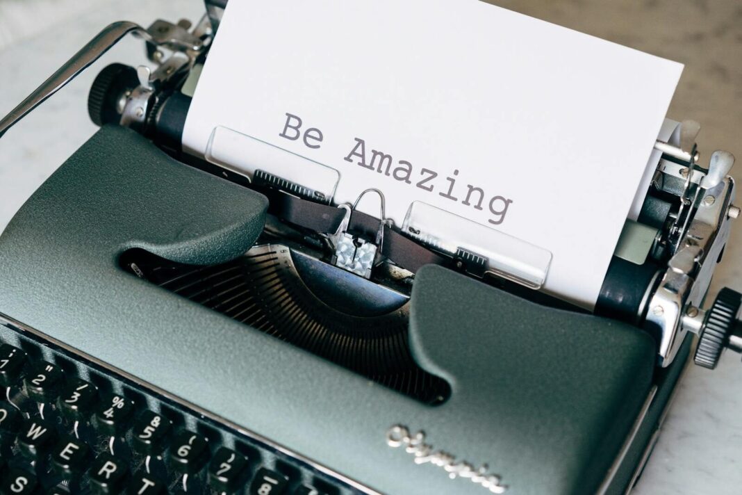 Close-up of a vintage typewriter typing 'Be Amazing' on white paper, conceptual style.