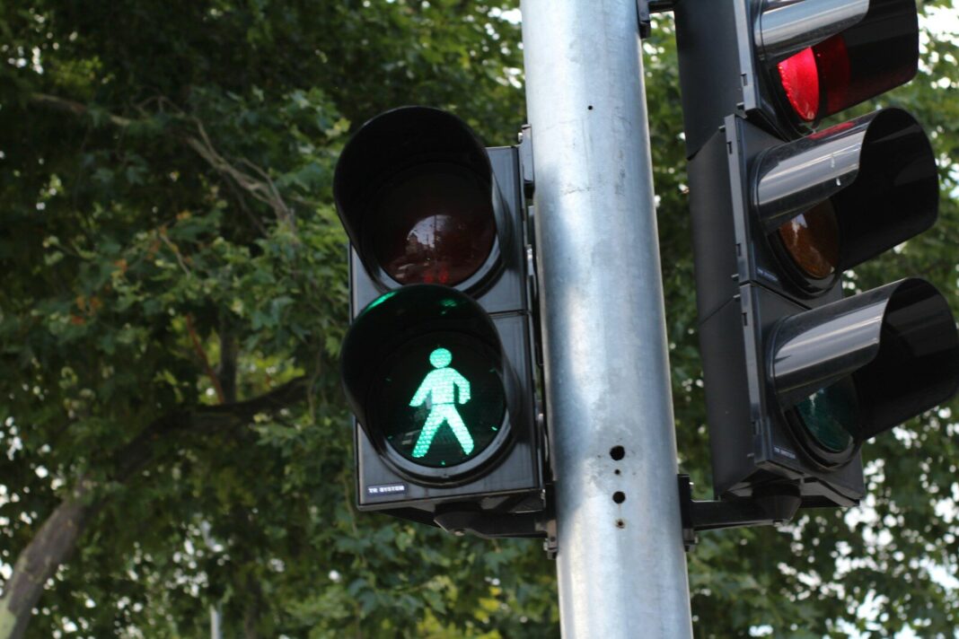 a traffic light with a green pedestrian sign on it