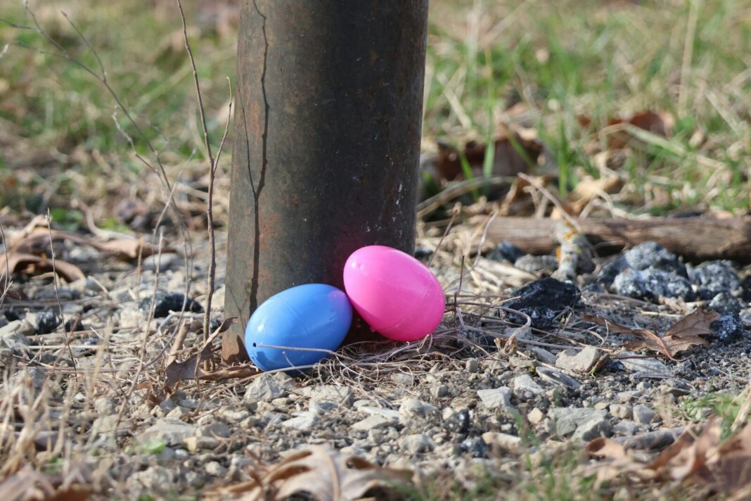 Two plastic easter eggs near a post