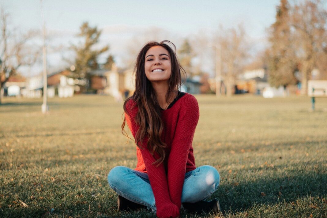 a woman sitting on the ground in a park